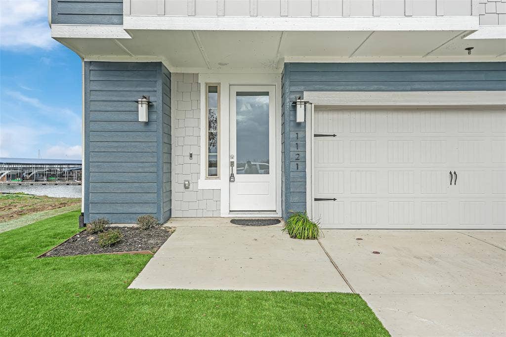 Property entrance with a water view, driveway, and a yard