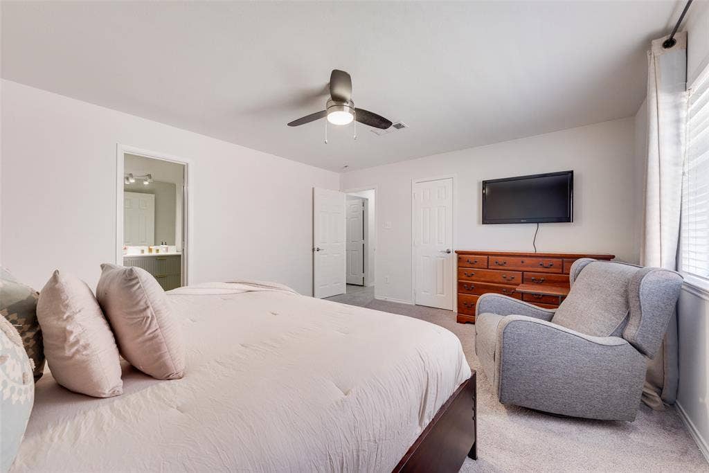 4104 Creekmeadow Drive, Carrollton, TX 75010 Interior room featuring neutral wall tones, wall-to-wall carpeting, a multi-blade ceiling fan with an integrated light fixture, and two interior doors with paneled detailing