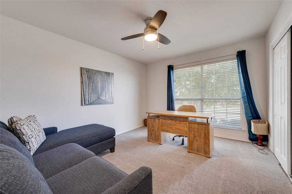 4104 Creekmeadow Drive, Carrollton, TX 75010 Neutral-toned wall-to-wall carpeting, ceiling fan with integrated lighting, large window with horizontal blinds, and a white paneled closet door