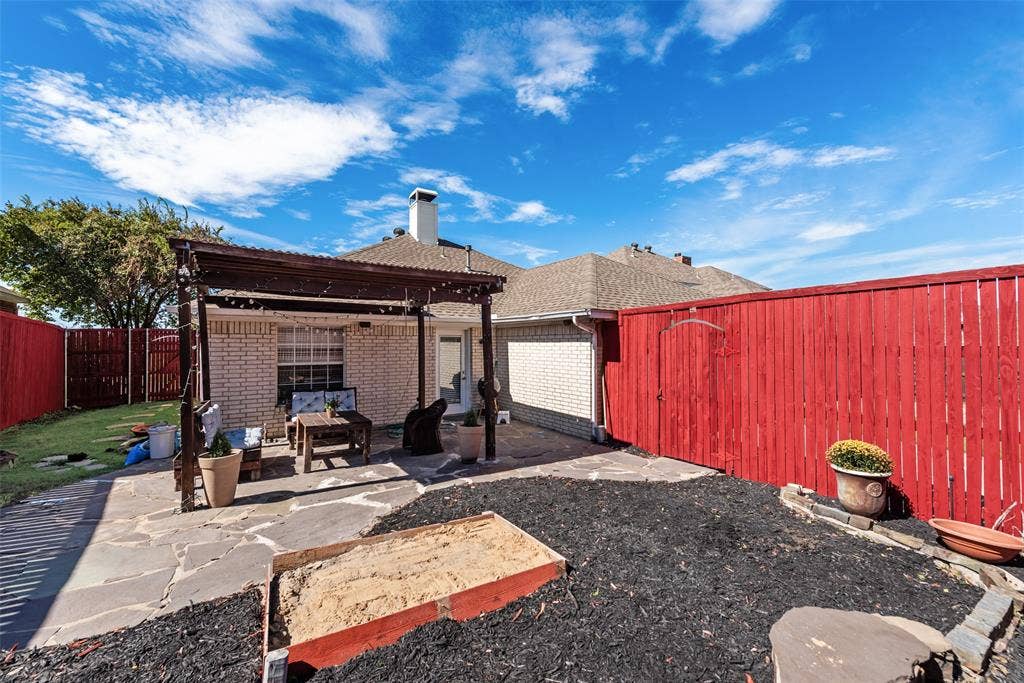 4104 Creekmeadow Drive, Carrollton, TX 75010 Backyard featuring a flagstone patio, wood-frame pergola, exterior brick cladding, and privacy fencing