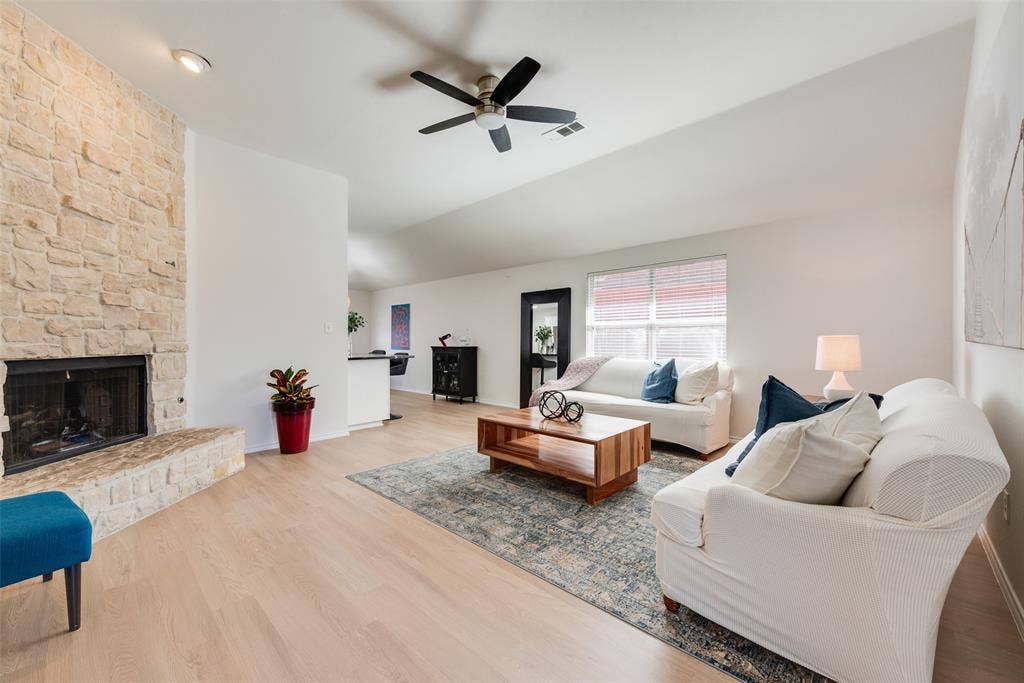 4104 Creekmeadow Drive, Carrollton, TX 75010 Stone-clad fireplace with a raised hearth, wood-finish flooring, vaulted ceiling, and ceiling fan