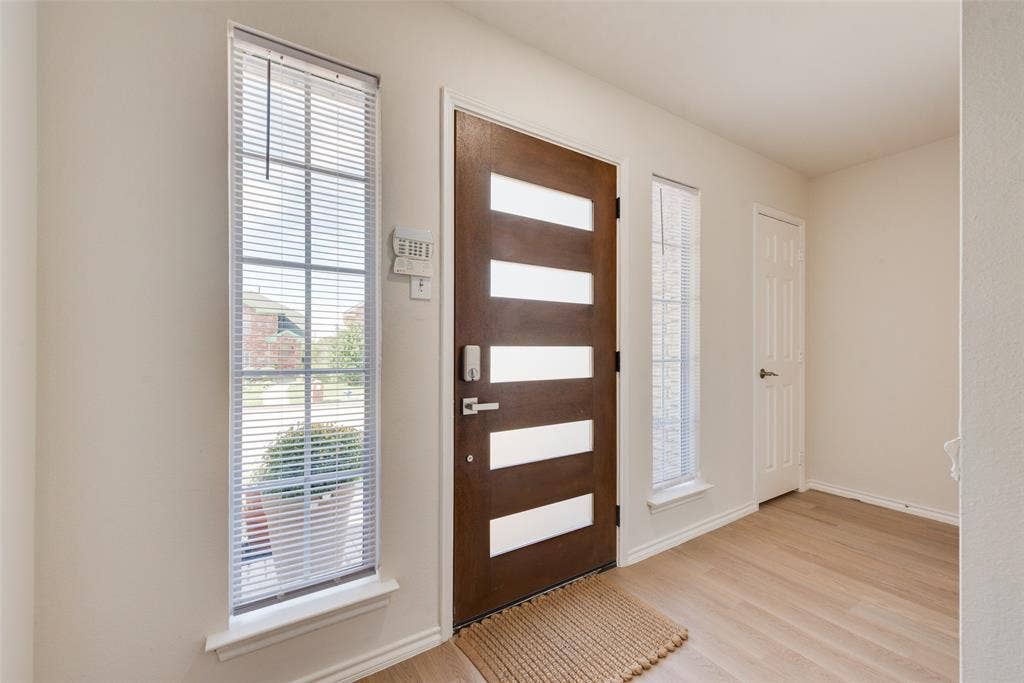 4104 Creekmeadow Drive, Carrollton, TX 75010 Entryway featuring a wood-finish door with horizontal glass panels, flanked by two tall windows, wood-finish flooring, and a six-panel door