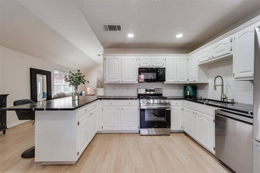 4104 Creekmeadow Drive, Carrollton, TX 75010 Kitchen featuring white cabinetry, dark stone-finish countertops, stainless steel appliances, and wood-finish flooring