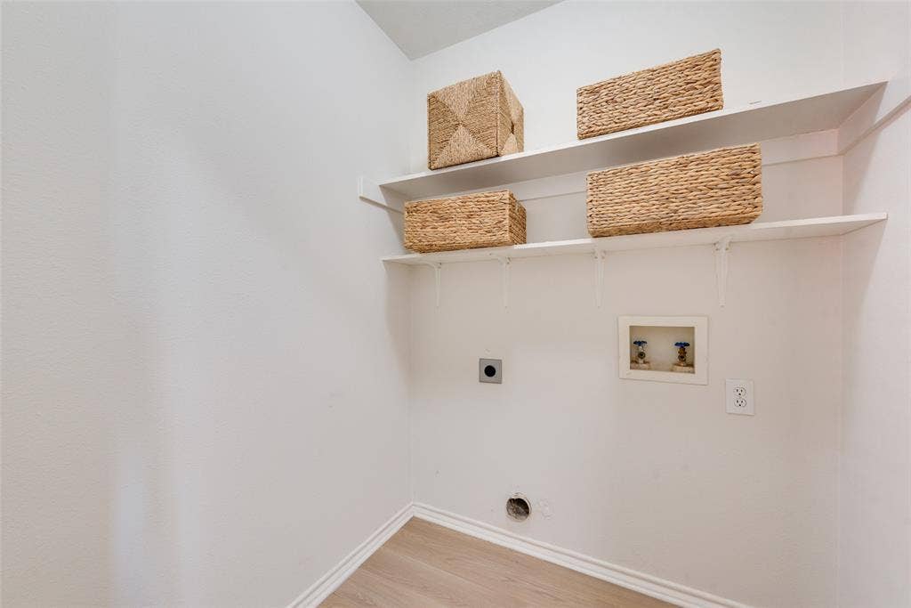 4104 Creekmeadow Drive, Carrollton, TX 75010 Utility space featuring two tiered wall-mounted shelves, wood-finish flooring, and dedicated water and electrical hookups