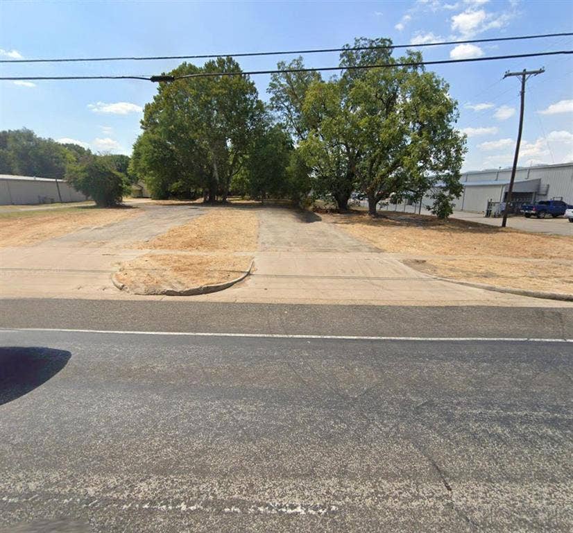 3110 W Gentry Parkway, Tyler, TX 75702 Level lot featuring asphalt paving, concrete curb cuts, and mature trees