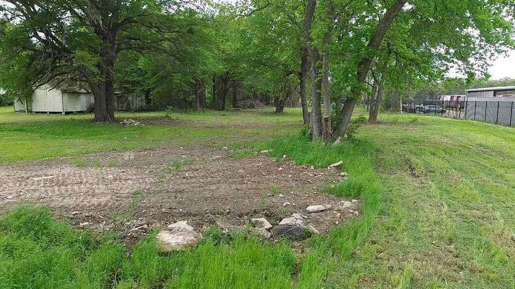 3110 W Gentry Parkway, Tyler, TX 75702 Expansive lot featuring mature trees, natural terrain, and a chain-link perimeter fence