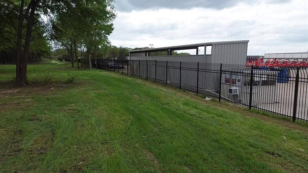 3110 W Gentry Parkway, Tyler, TX 75702 Level green space featuring established trees and perimeter metal fencing