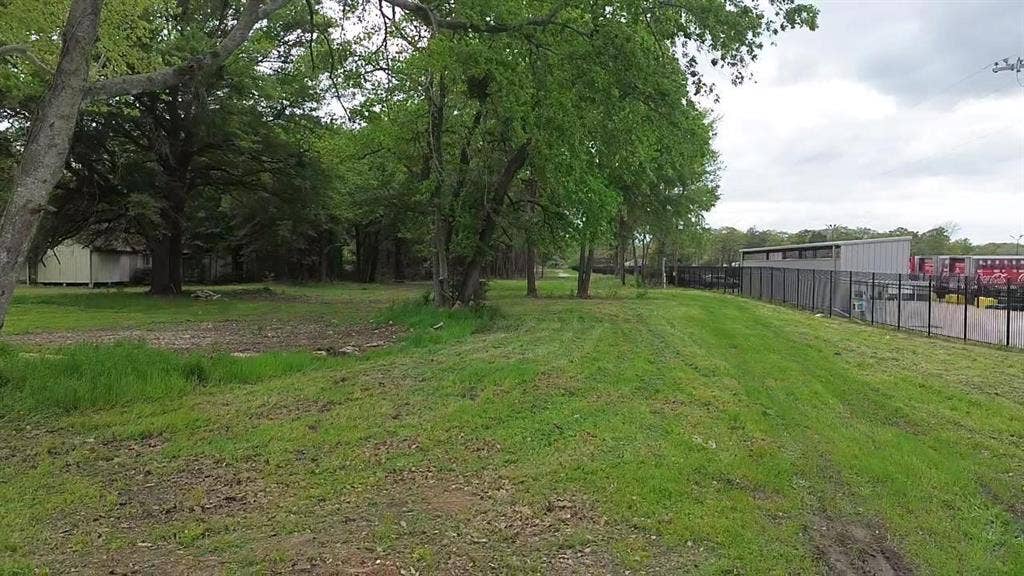 3110 W Gentry Parkway, Tyler, TX 75702 Expansive lot featuring mature hardwood trees and perimeter metal fencing