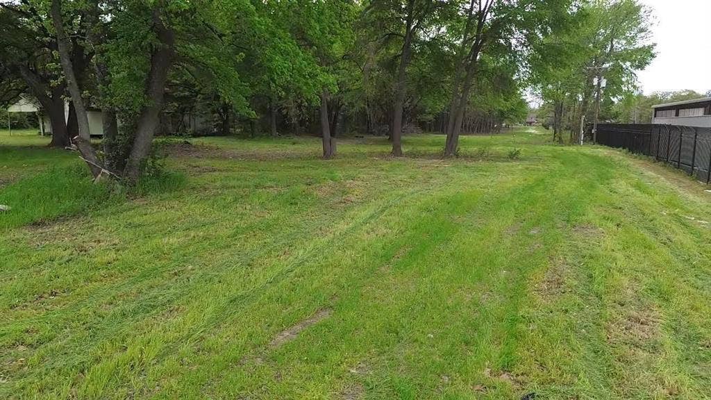 3110 W Gentry Parkway, Tyler, TX 75702 Expansive lot featuring mature trees, natural terrain, and perimeter metal fencing