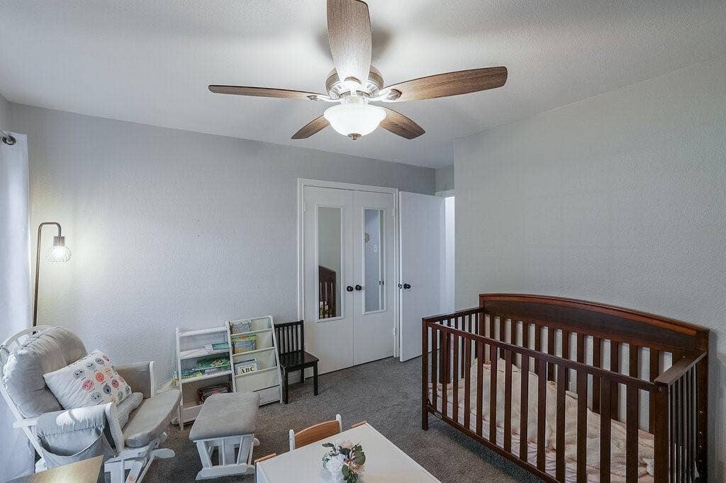 Room featuring neutral-toned walls, carpeting, a ceiling fan with integrated lighting, and dual-panel closet doors with inset mirrors