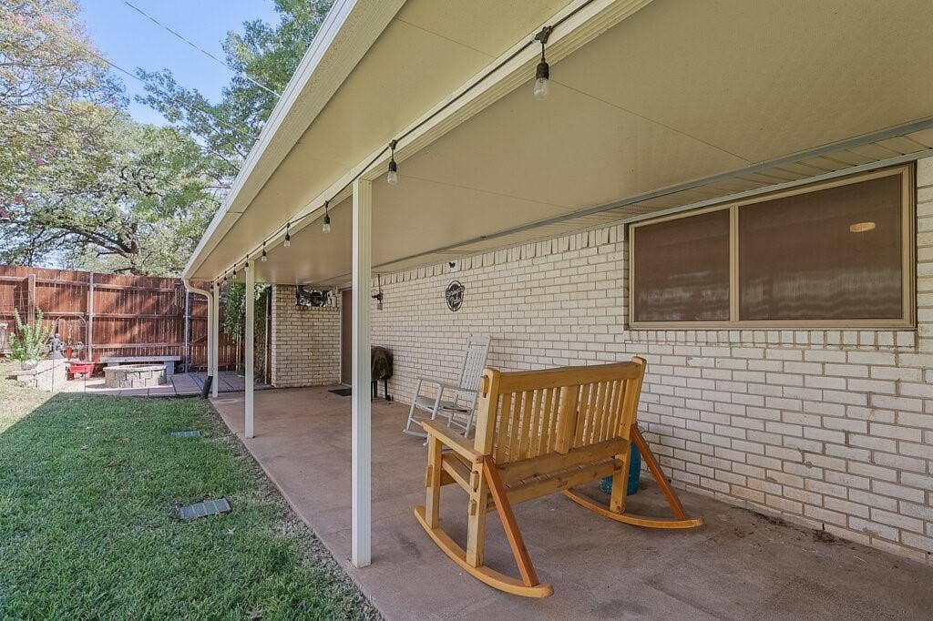 Covered patio featuring a concrete floor, painted brick exterior wall, and integrated string lighting