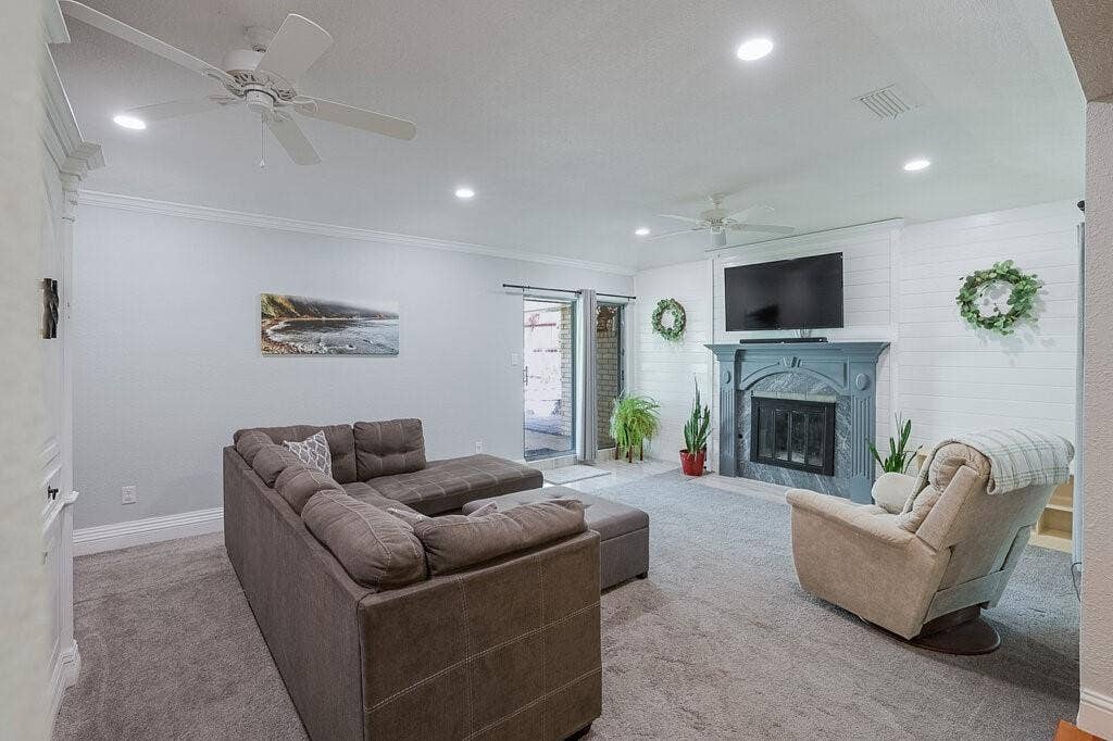 Living space featuring recessed lighting, ceiling fans, shiplap wall accent, and a fireplace with a decorative mantel