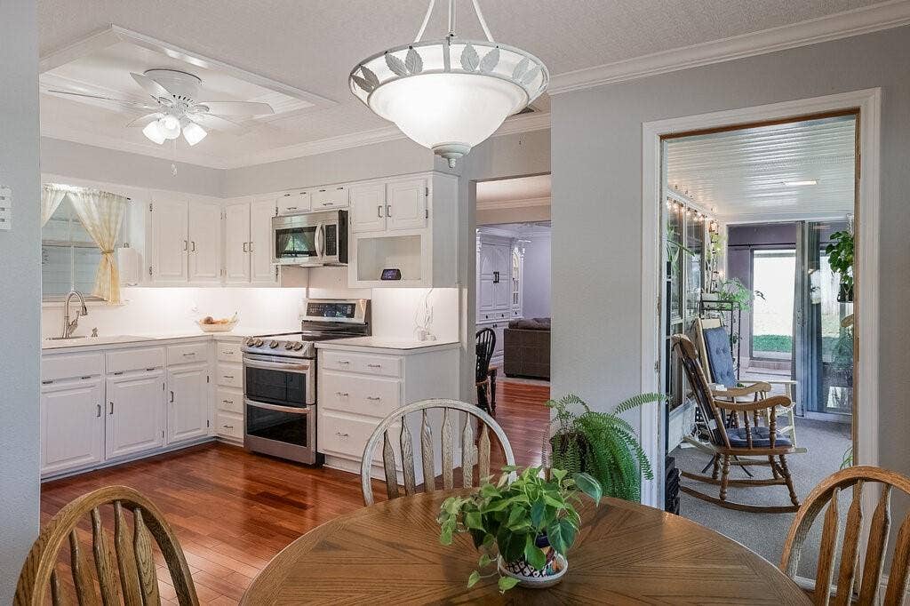 Kitchen featuring white cabinetry, stainless steel appliances, wood-finish flooring, recessed ceiling lighting, and a pendant light fixture