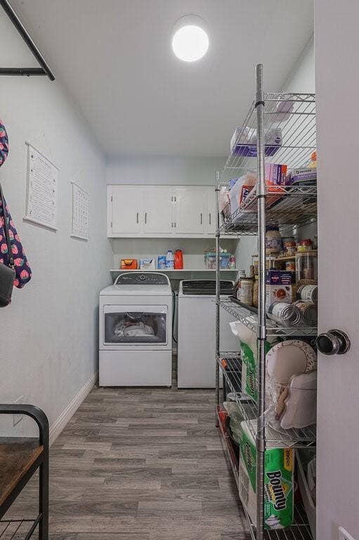 Laundry room featuring wood-finish flooring, white overhead cabinetry, an open shelving unit, and a flush-mount ceiling light
