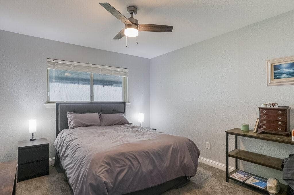 Bedroom featuring neutral wall paint, carpeted flooring, and a ceiling fan with integrated lighting