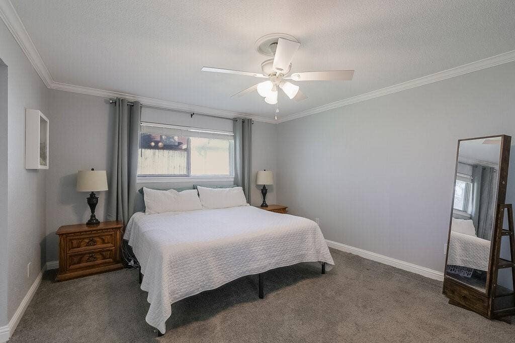 Bedroom featuring neutral wall paint, crown molding, wall-to-wall carpeting, and a ceiling fan with integrated lighting