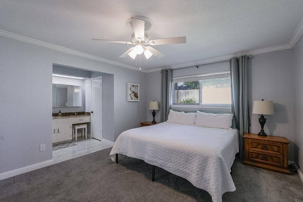 Bedroom featuring crown molding, neutral wall color, carpeted flooring, and a ceiling-mounted light fixture with a fan