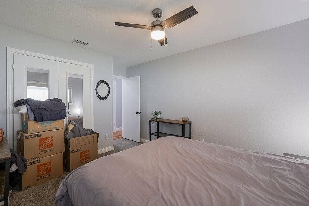 Room featuring neutral-toned walls, carpeting, a ceiling fan with integrated lighting, and a dual-door closet with mirrored panels