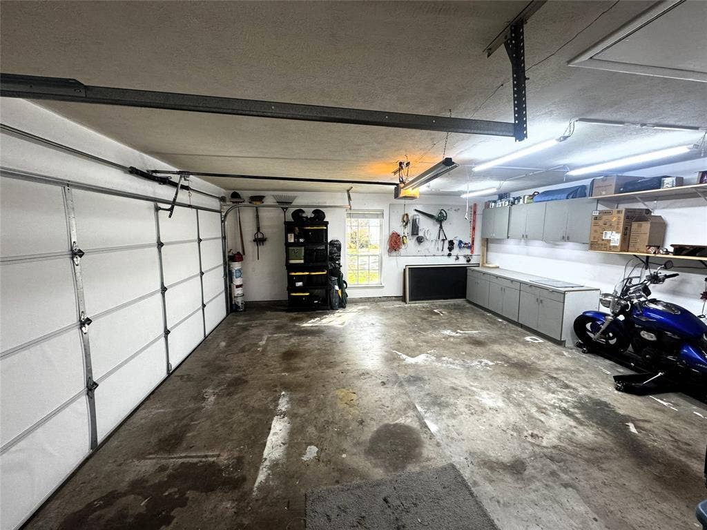 Multi-car garage featuring built-in cabinetry, overhead shelving, industrial-style lighting, and a window