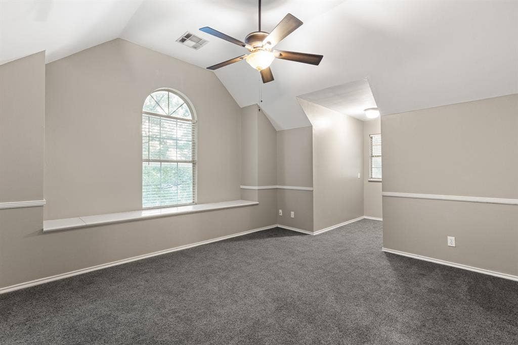 207 Westlane Circle, Woodway, TX 76712 Vaulted ceilings featuring an arched window, a built-in window seat, chair rail molding, and a ceiling fan