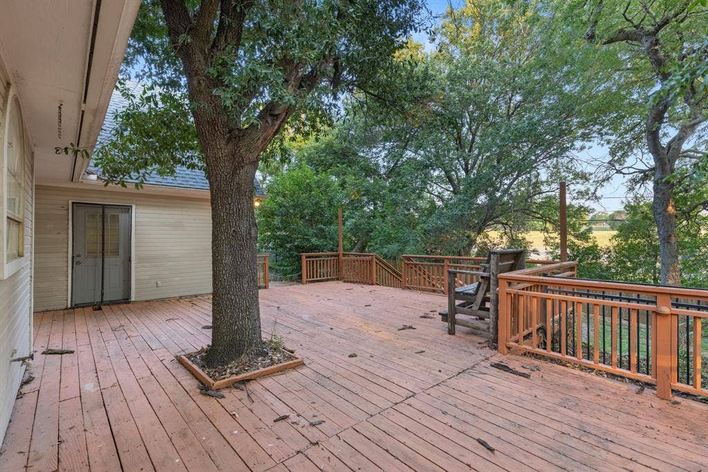207 Westlane Circle, Woodway, TX 76712 Expansive elevated wood deck featuring integrated mature tree landscaping, wooden railing with metal balusters, and stairs leading to lower-level exterior space