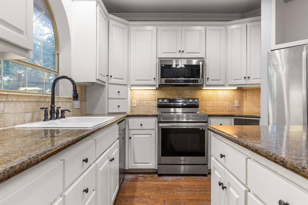207 Westlane Circle, Woodway, TX 76712 Kitchen featuring white cabinetry, stone countertops, stainless steel appliances, a tile backsplash, and a farmhouse-style sink with a matte black faucet