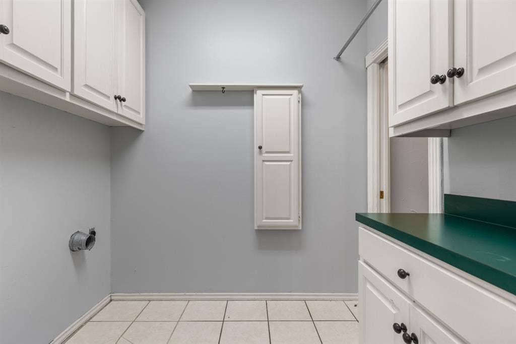 207 Westlane Circle, Woodway, TX 76712 Laundry room featuring white cabinetry, a wall-mounted storage cabinet with a shelf, a metal hanging rod, and tile flooring