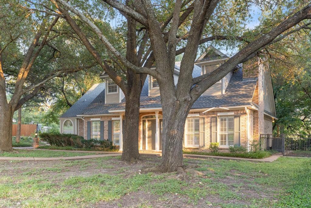 207 Westlane Circle, Woodway, TX 76712 Two-story brick exterior featuring a multi-gabled roofline, dormer windows, shutters, and mature trees
