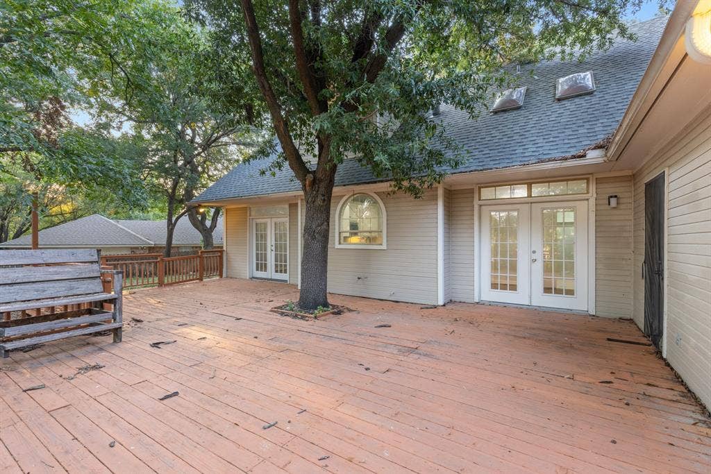 207 Westlane Circle, Woodway, TX 76712 Expansive wooden deck featuring built-in seating, dual sets of French doors, an integrated mature tree, and roof-mounted skylights