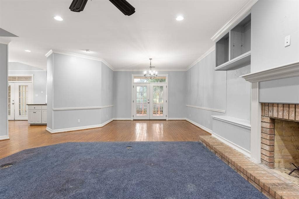 207 Westlane Circle, Woodway, TX 76712 Living area featuring wood-finish flooring, a fireplace with a brick surround, built-in cabinetry, recessed lighting, and double glass pane doors