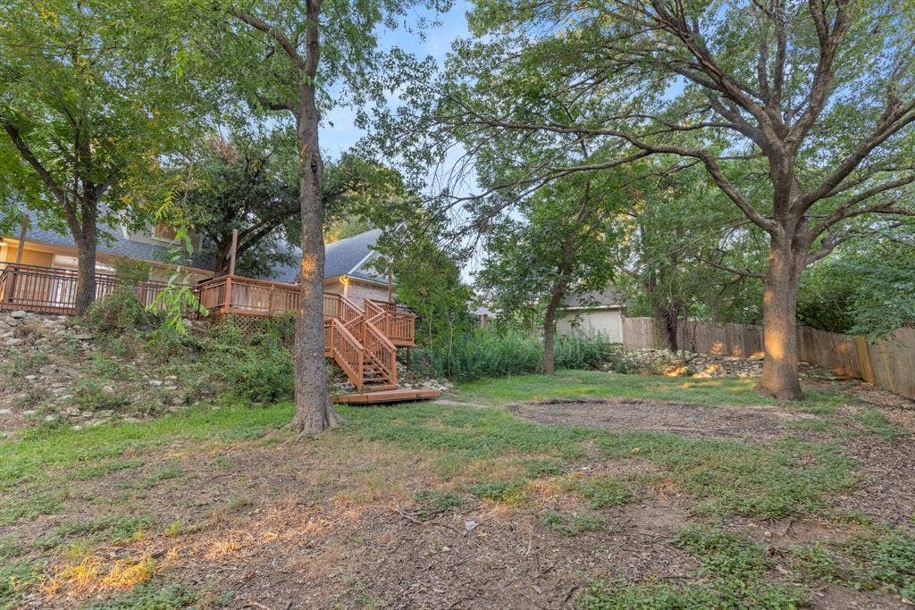 207 Westlane Circle, Woodway, TX 76712 Multi-level wood deck with stairs, stone retaining wall, and mature trees on a spacious lot