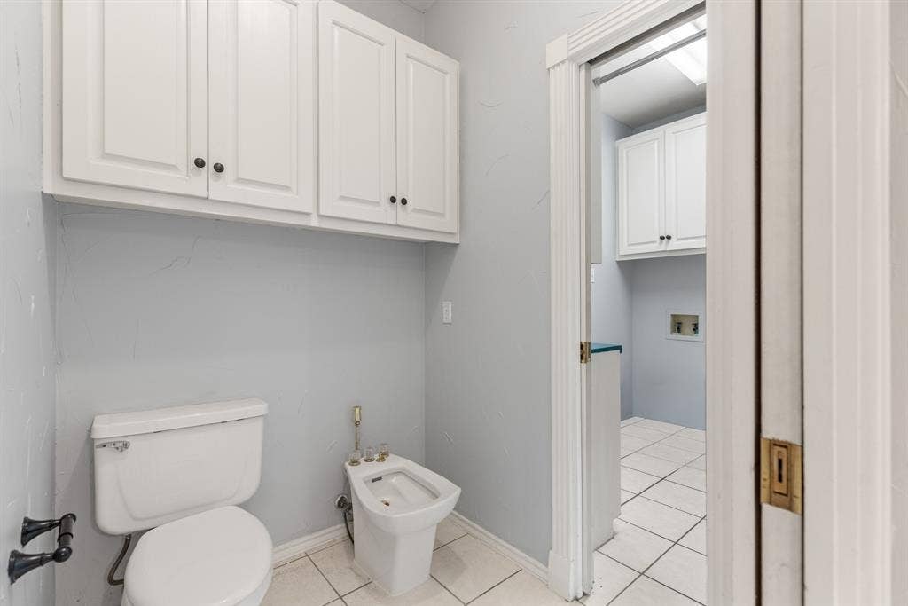 207 Westlane Circle, Woodway, TX 76712 Bathroom featuring white cabinetry, ceramic tile flooring, a porcelain toilet, and a bidet