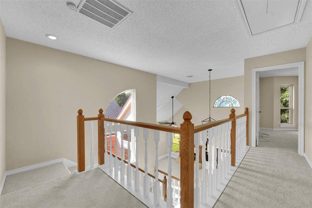 1920 Keystone Drive, Plano, TX 75075 Wood-capped staircase railing with painted balusters, arched windows, and wall-to-wall carpeting