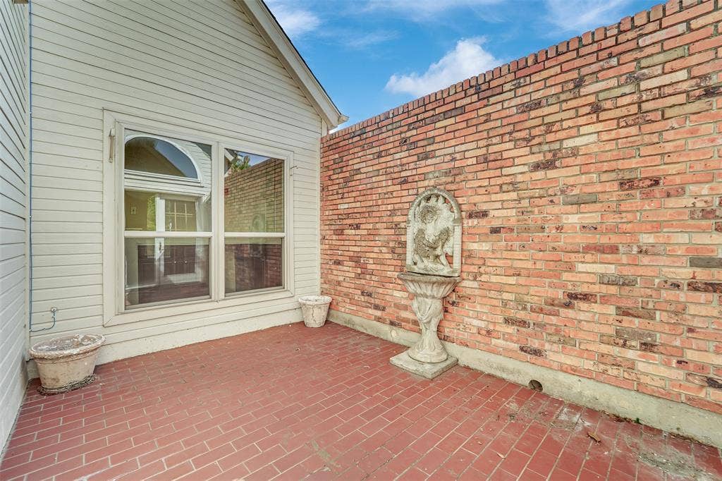 1920 Keystone Drive, Plano, TX 75075 Enclosed courtyard featuring red brick masonry flooring, a perimeter brick wall, a built-in stone fountain, and horizontal siding exterior