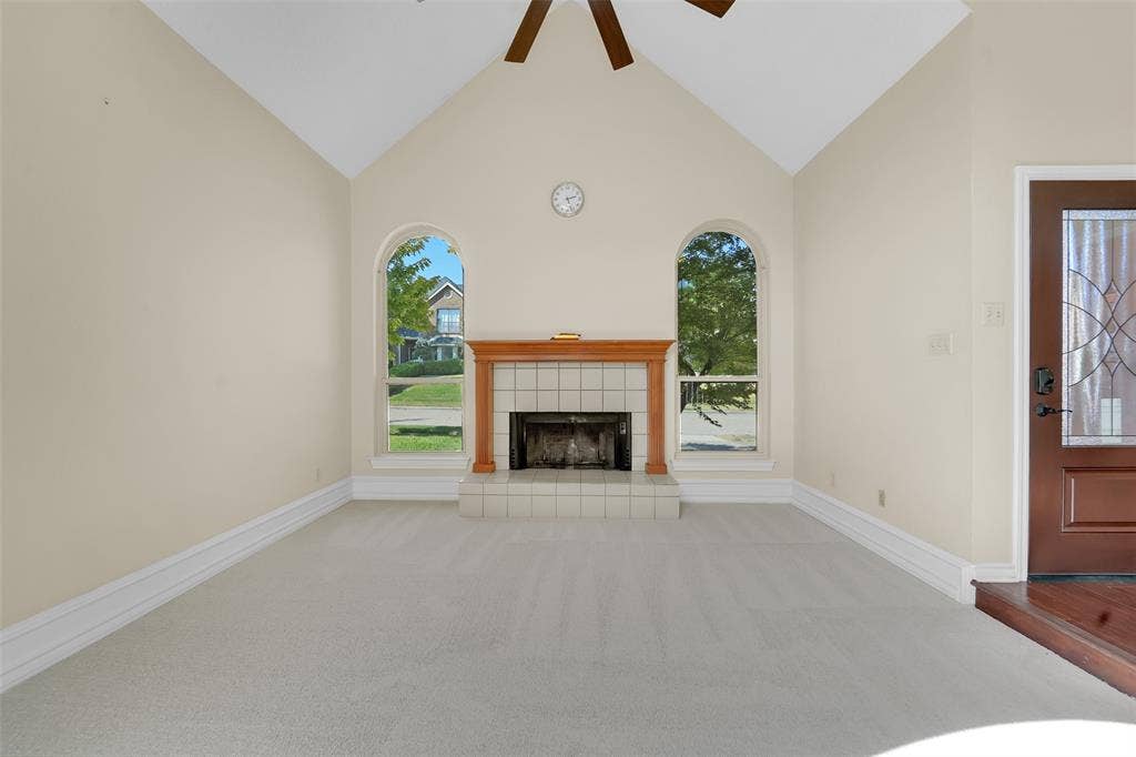 1920 Keystone Drive, Plano, TX 75075 Vaulted ceiling featuring a central ceiling fan, fireplace with a wood mantel and tile surround, and arched windows