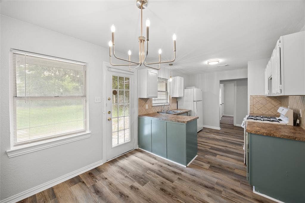 1605 Proctor Drive, Grand Prairie, TX 75051 Eat-in kitchen featuring wood-finish flooring, white walls, and a multi-light chandelier