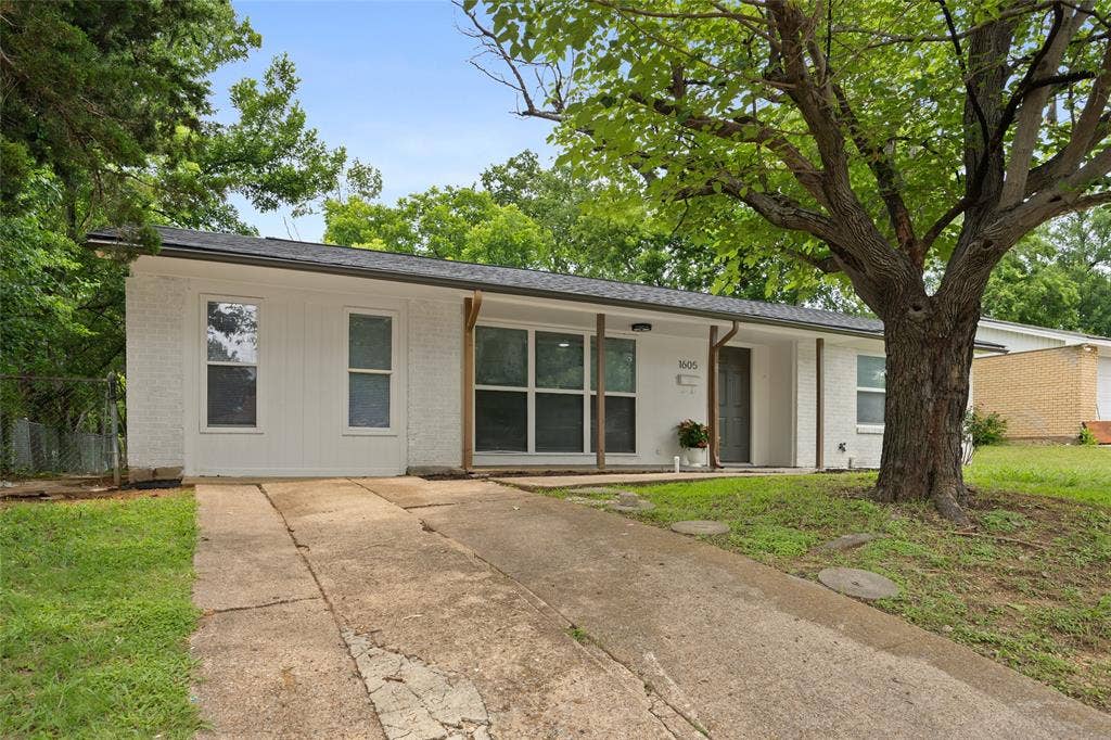 1605 Proctor Drive, Grand Prairie, TX 75051 White brick exterior with a dark grey roof and contrasting wood-tone columns