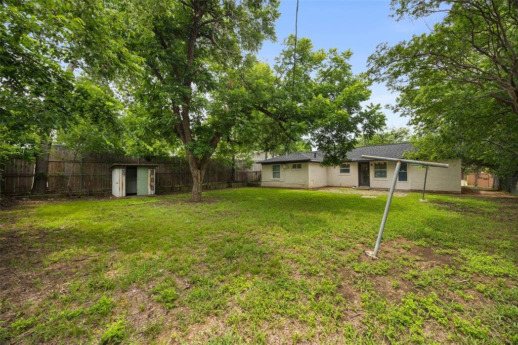 1605 Proctor Drive, Grand Prairie, TX 75051 Spacious backyard featuring established trees, a storage shed, and a privacy fence