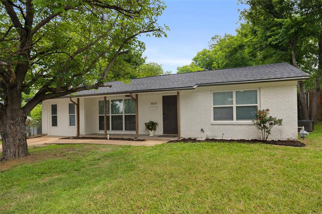 1605 Proctor Drive, Grand Prairie, TX 75051 White brick exterior with a dark shingle roof and a spacious front yard