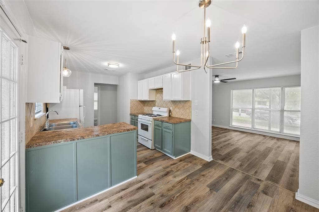 1605 Proctor Drive, Grand Prairie, TX 75051 Open-concept kitchen featuring white upper cabinetry, sage green lower cabinetry, wood-finish flooring, and a contemporary chandelier