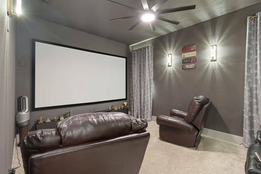 12173 Deer Trail, Frisco, TX 75035 Media room featuring a fixed projection screen, neutral carpeting, a multi-blade ceiling fan with integrated lighting, and dual wall-mounted light fixtures
