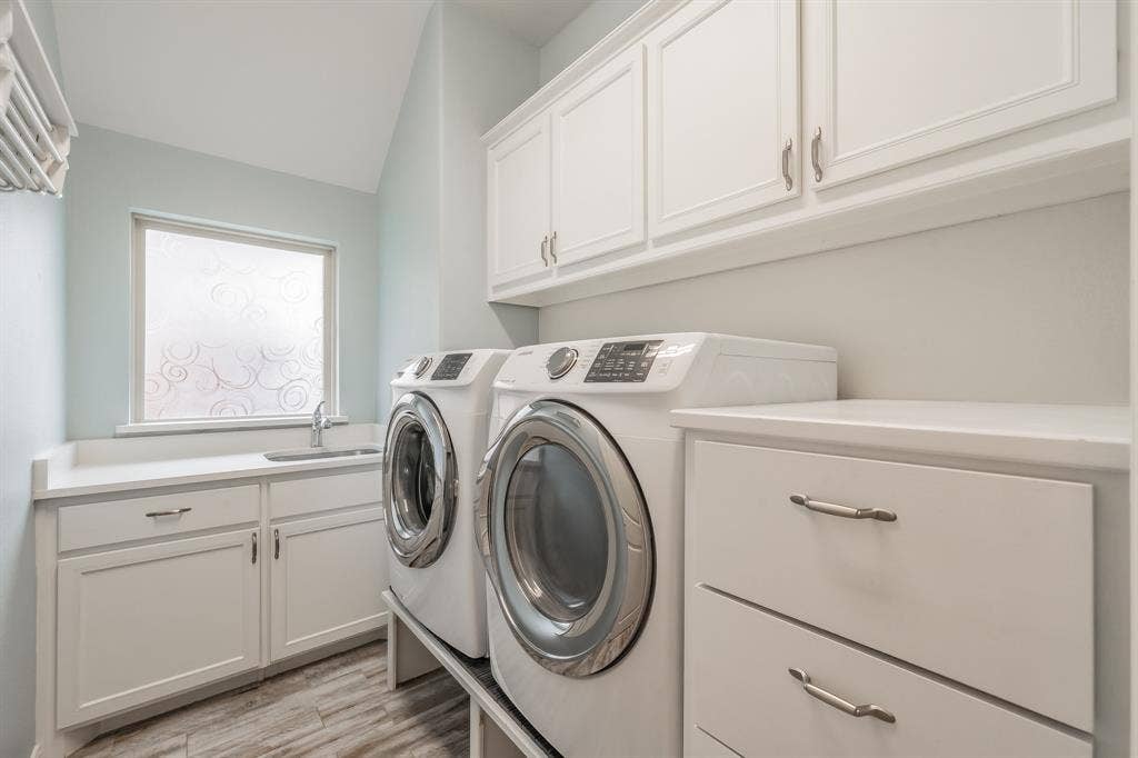 Laundry room with separate washer and dryer, cabinet space, and light wood finished floors