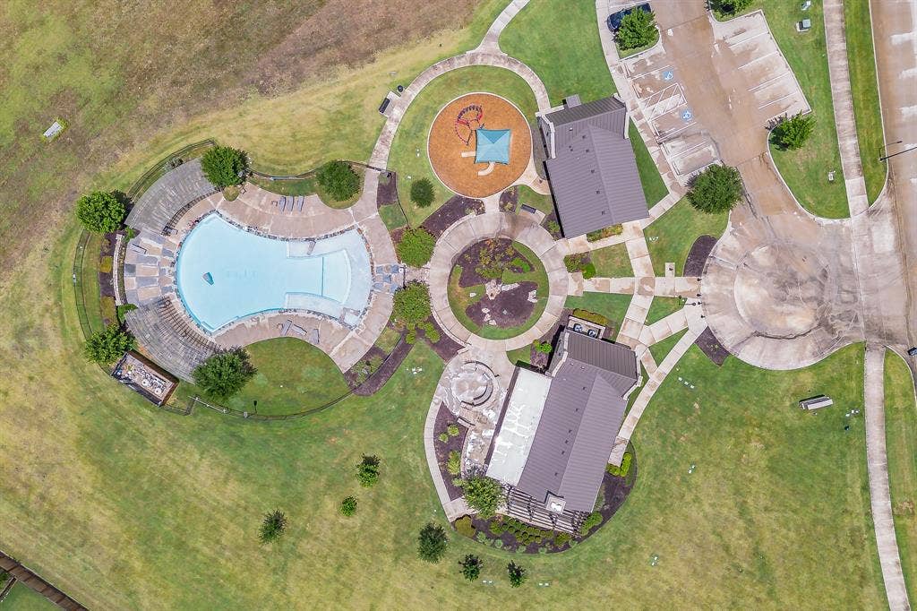 Community recreation area featuring a large swimming pool, playground, two amenity buildings, and paved pathways