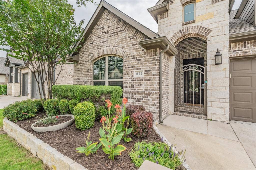 Property entrance with brick siding, stone siding, driveway, and a shingled roof