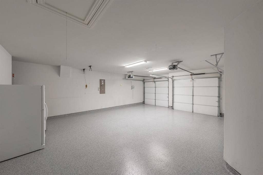 Garage featuring freestanding refrigerator, electric panel, and a garage door opener