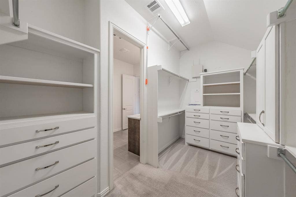 Spacious closet featuring vaulted ceiling and light colored carpet