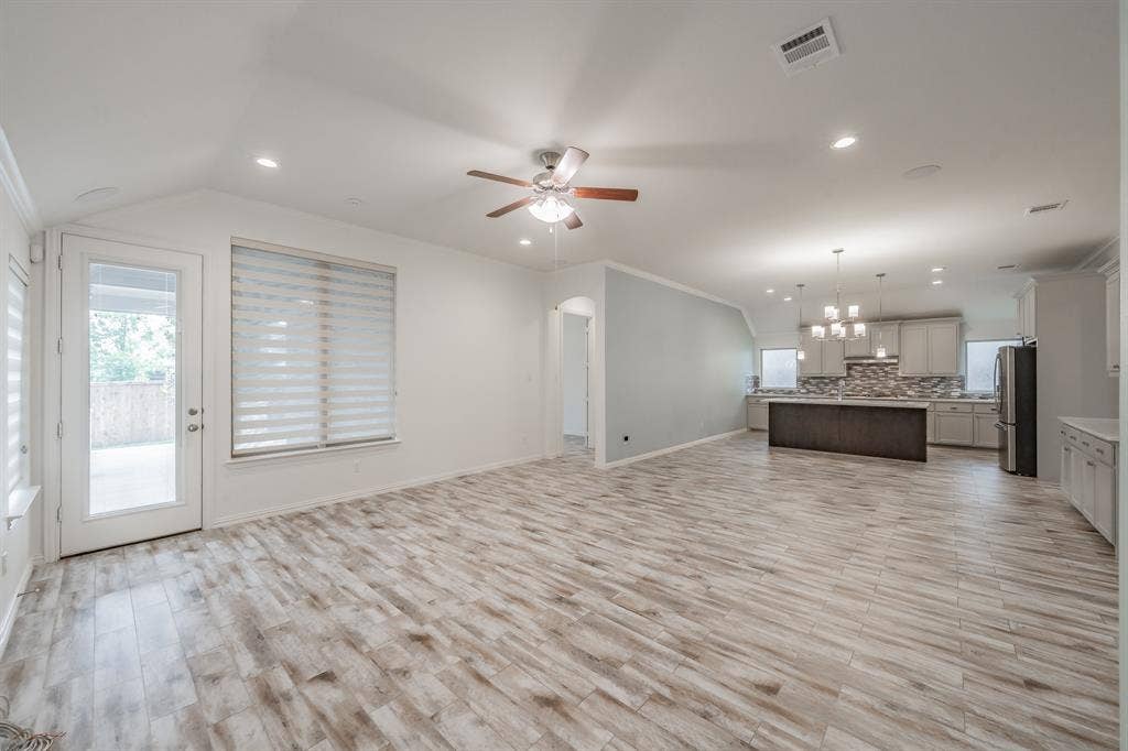 Unfurnished living room featuring a ceiling fan, light wood finished floors, a chandelier, recessed lighting, and baseboards