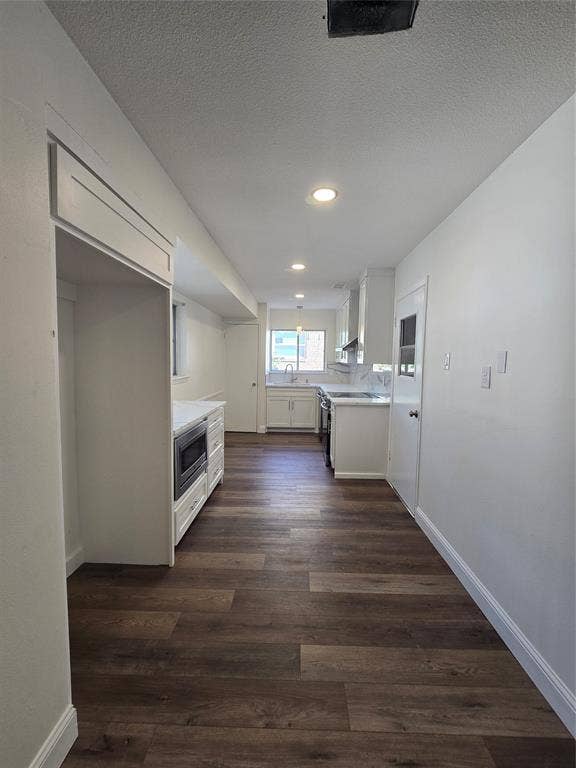 Kitchen featuring wood-finish flooring, white cabinetry, integrated microwave, and recessed lighting