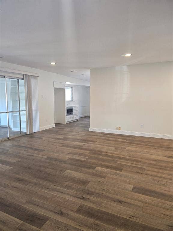 Open floor plan featuring wood-finish flooring, recessed lighting, sliding glass doors, and built-in shelving