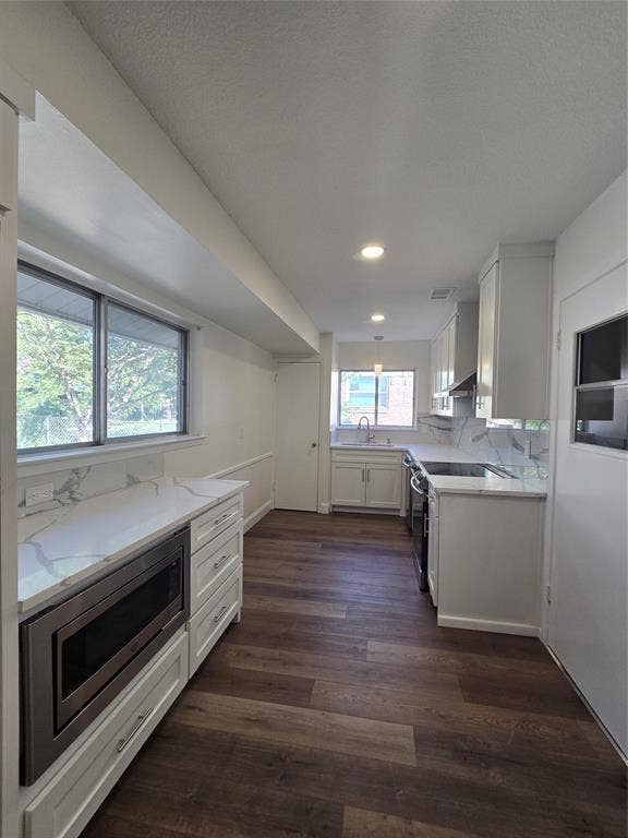 Kitchen featuring white cabinetry, stone-finish countertops, wood-finish flooring, recessed lighting, and a built-in microwave